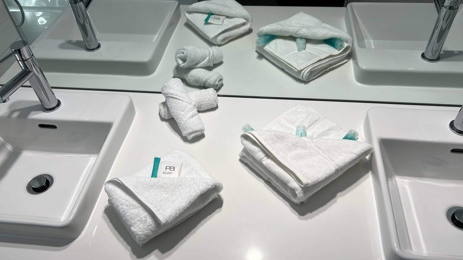 Twin vanity presented with folded towels and guest amenities