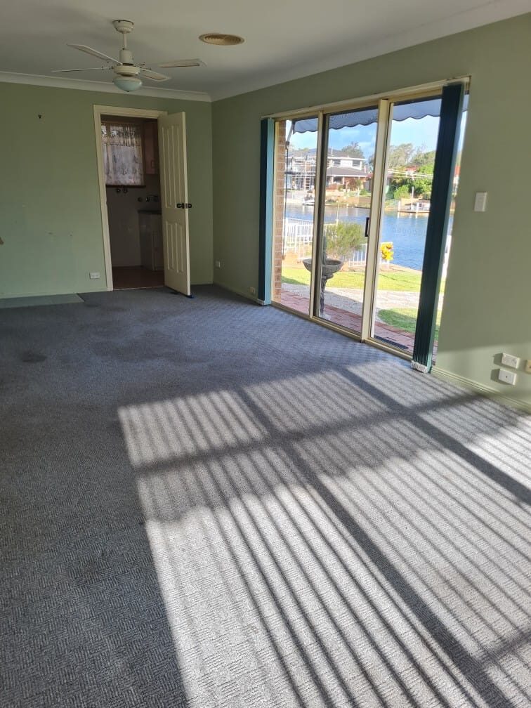Empty waterfront living room with freshly cleaned carpet ready for handover
