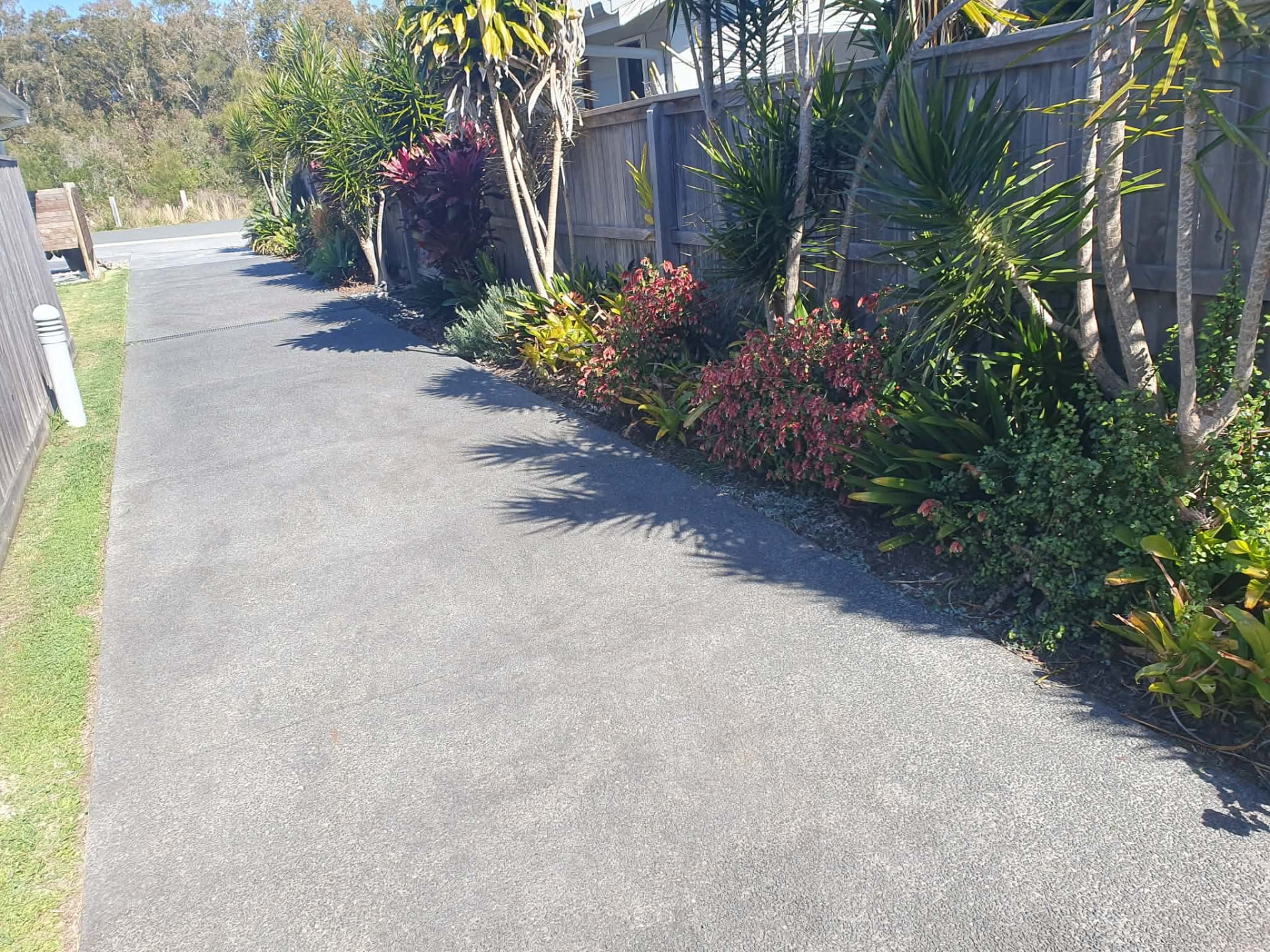 Driveway edges trimmed and garden bed tidied along a side fence